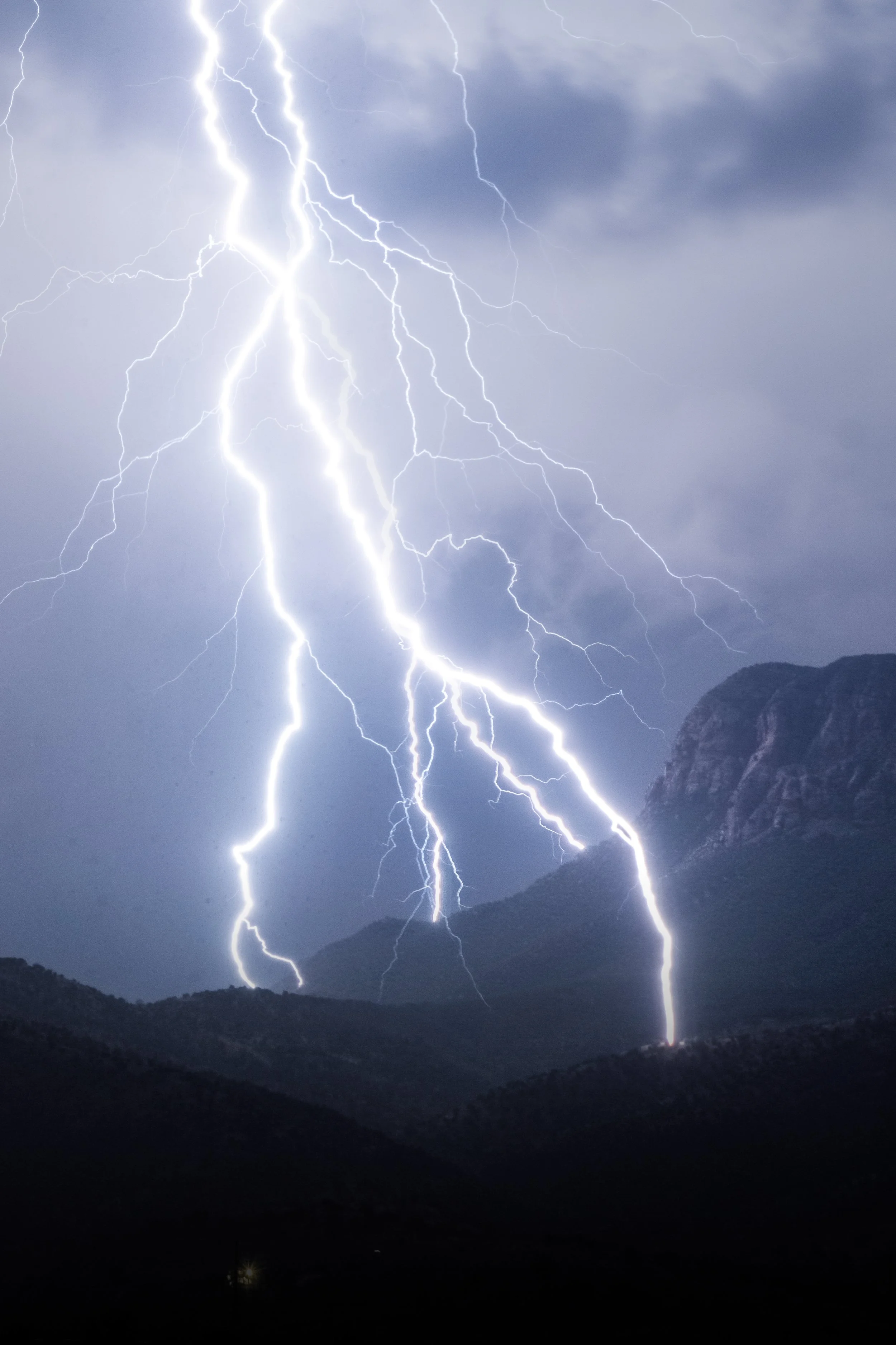 Lightning strikes over mountainous landscape during a thunderstorm.