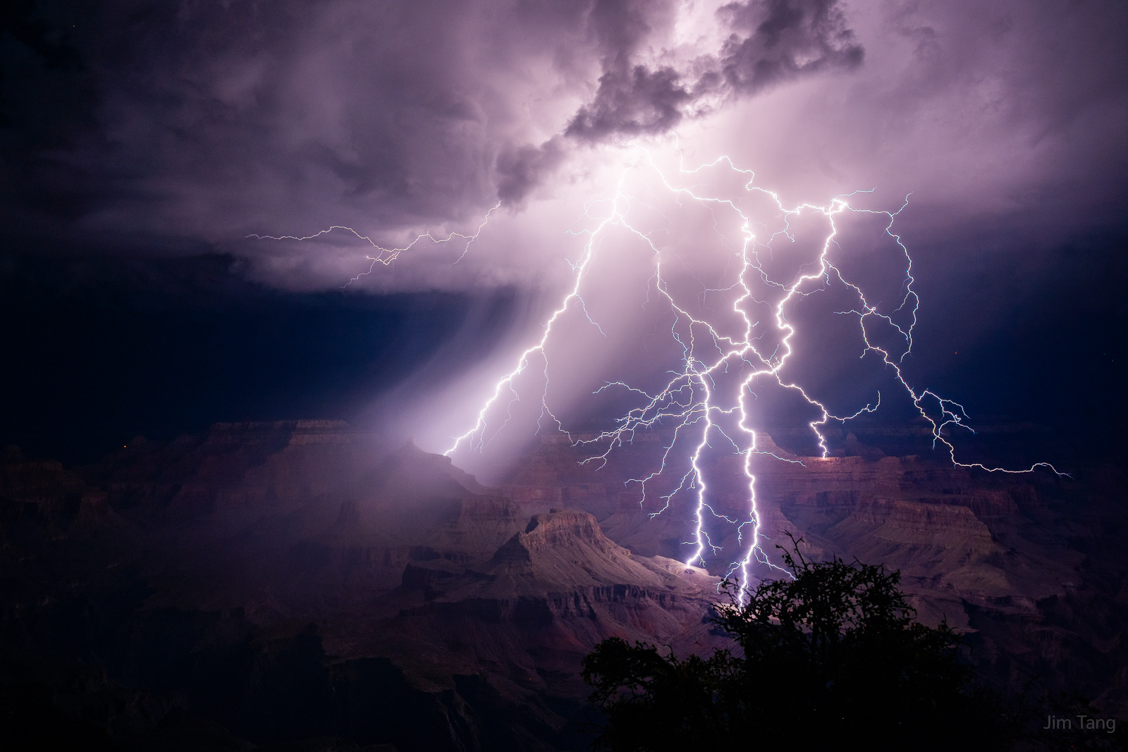 Bright lightning strikes over the Grand Canyon during a thunderstorm at night.