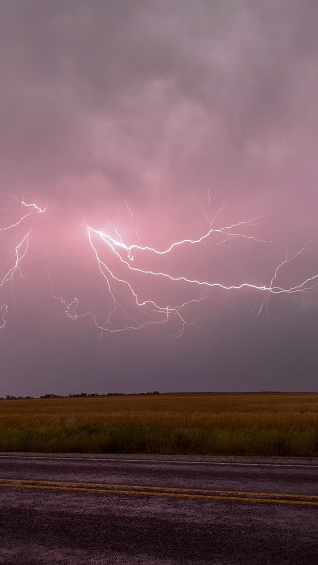 Pink lightning branching over open countryside
