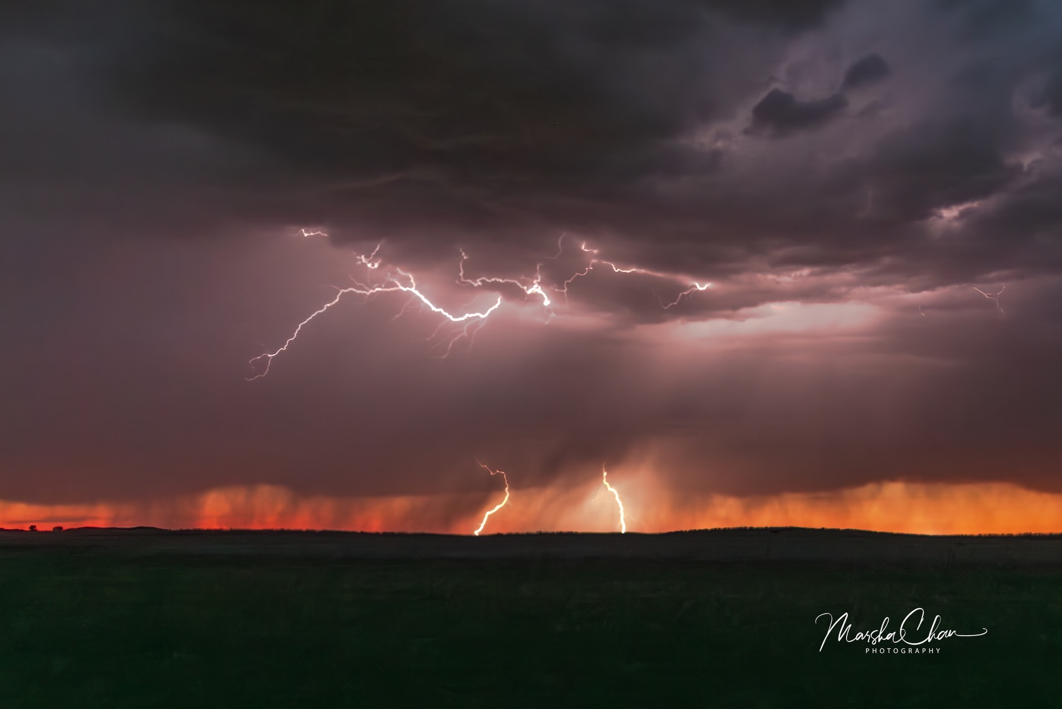 Lightning beneath dark clouds and a red sunset