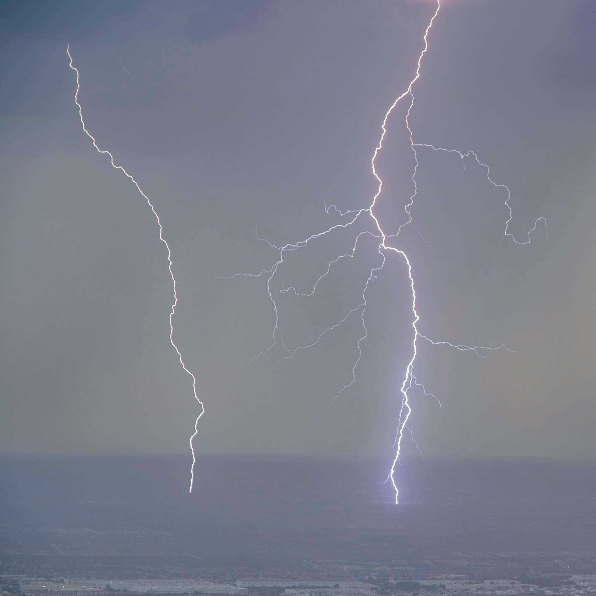 Two lightning bolts over a distant landscape