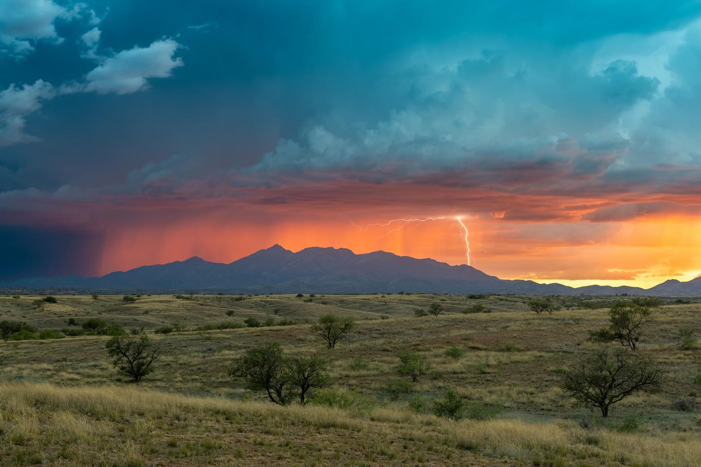 Distant lightning below colorful sunset clouds