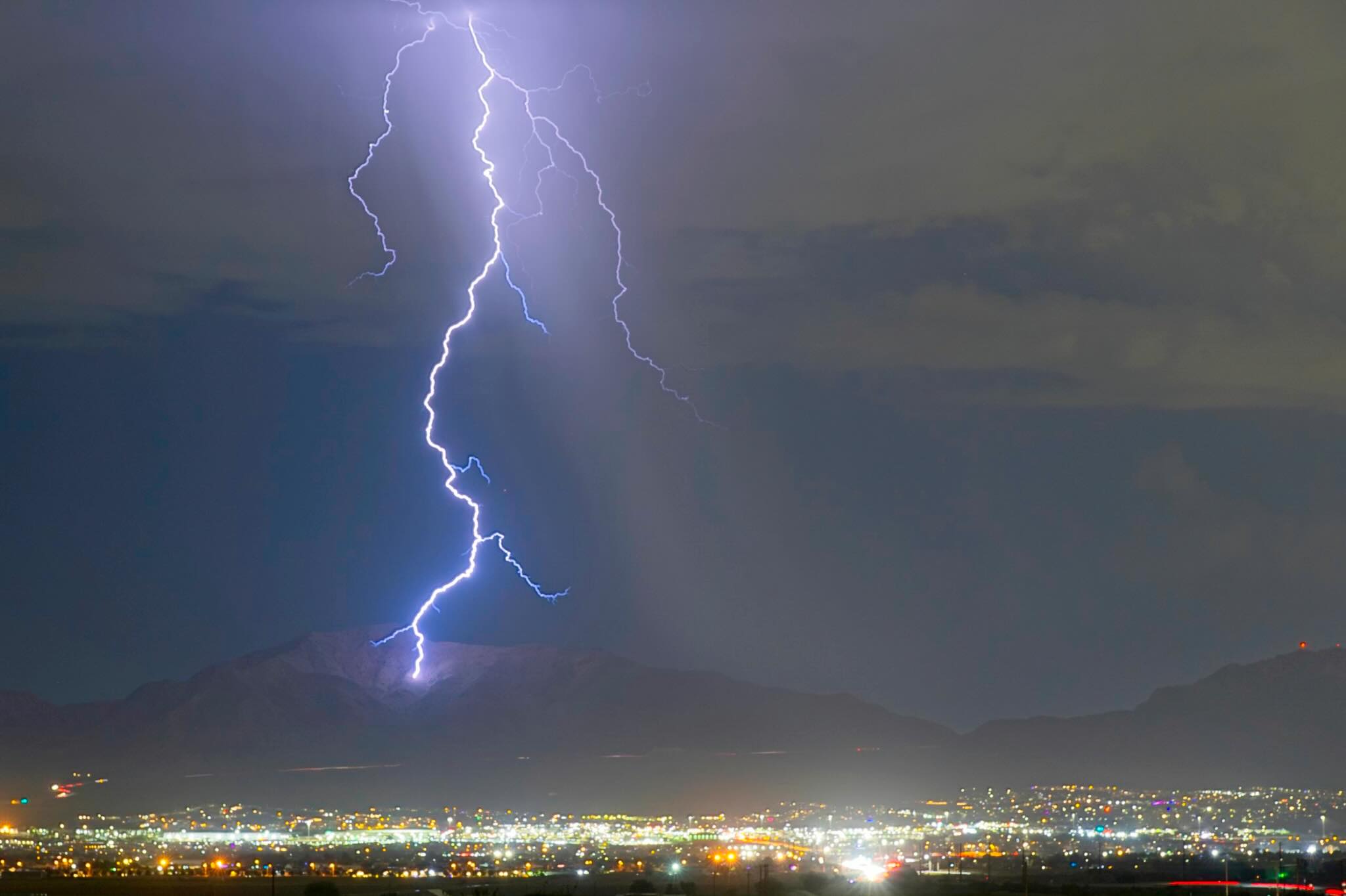Lightning above mountains and city lights