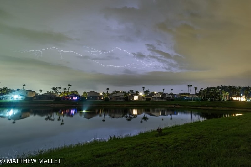 Cloud-to-cloud lightning reflected in a lake at night