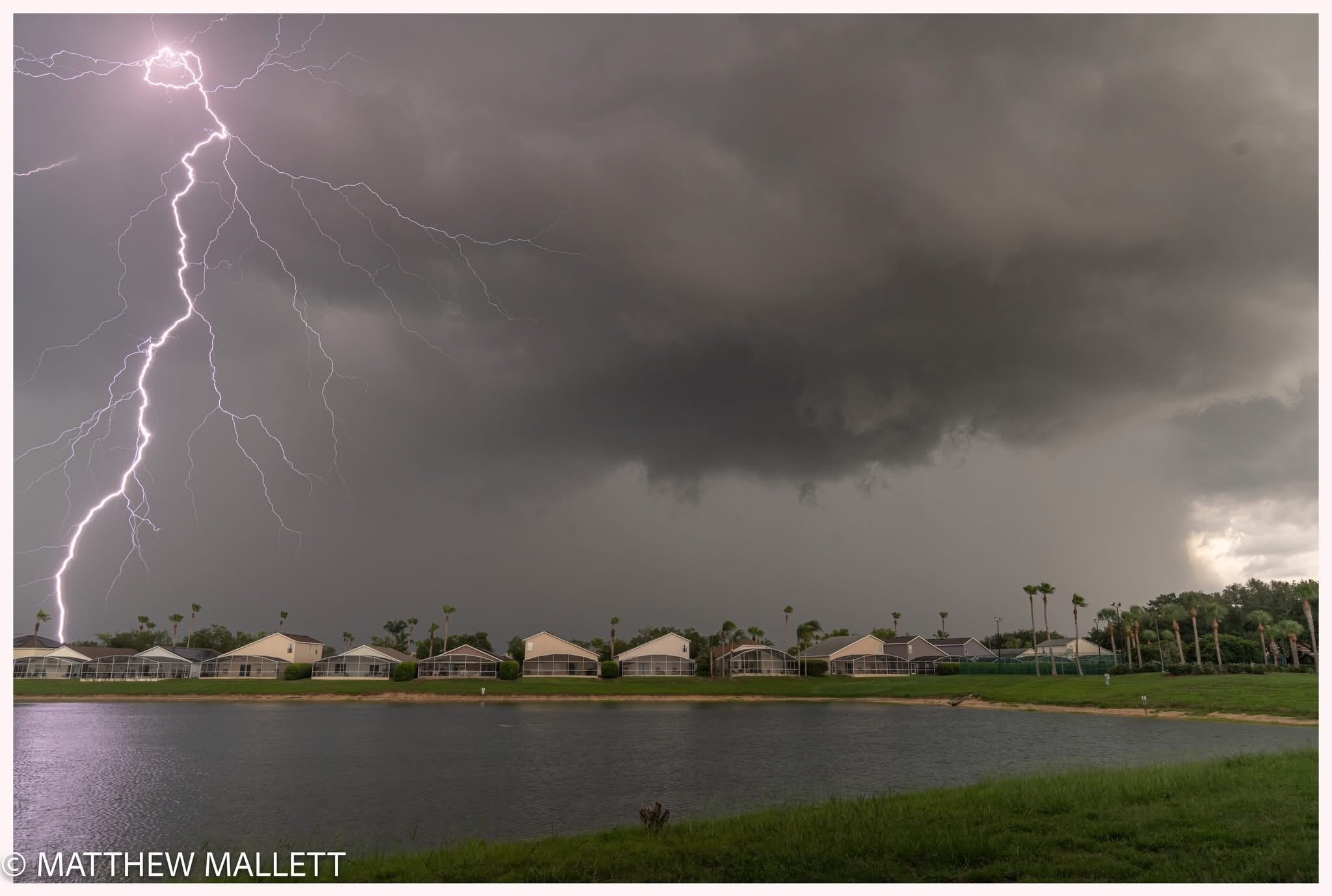 A bright lightning bolt beside a neighborhood lake