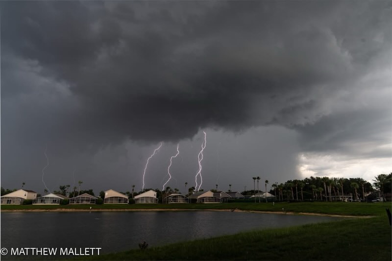 Lightning beneath a dark storm over a neighborhood