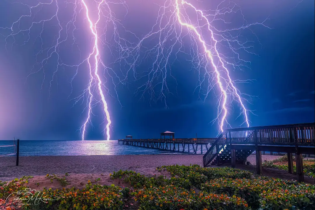 Bright lightning bolts near a coastal pier