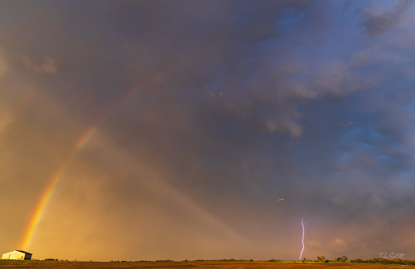 A rainbow and distant lightning at sunset