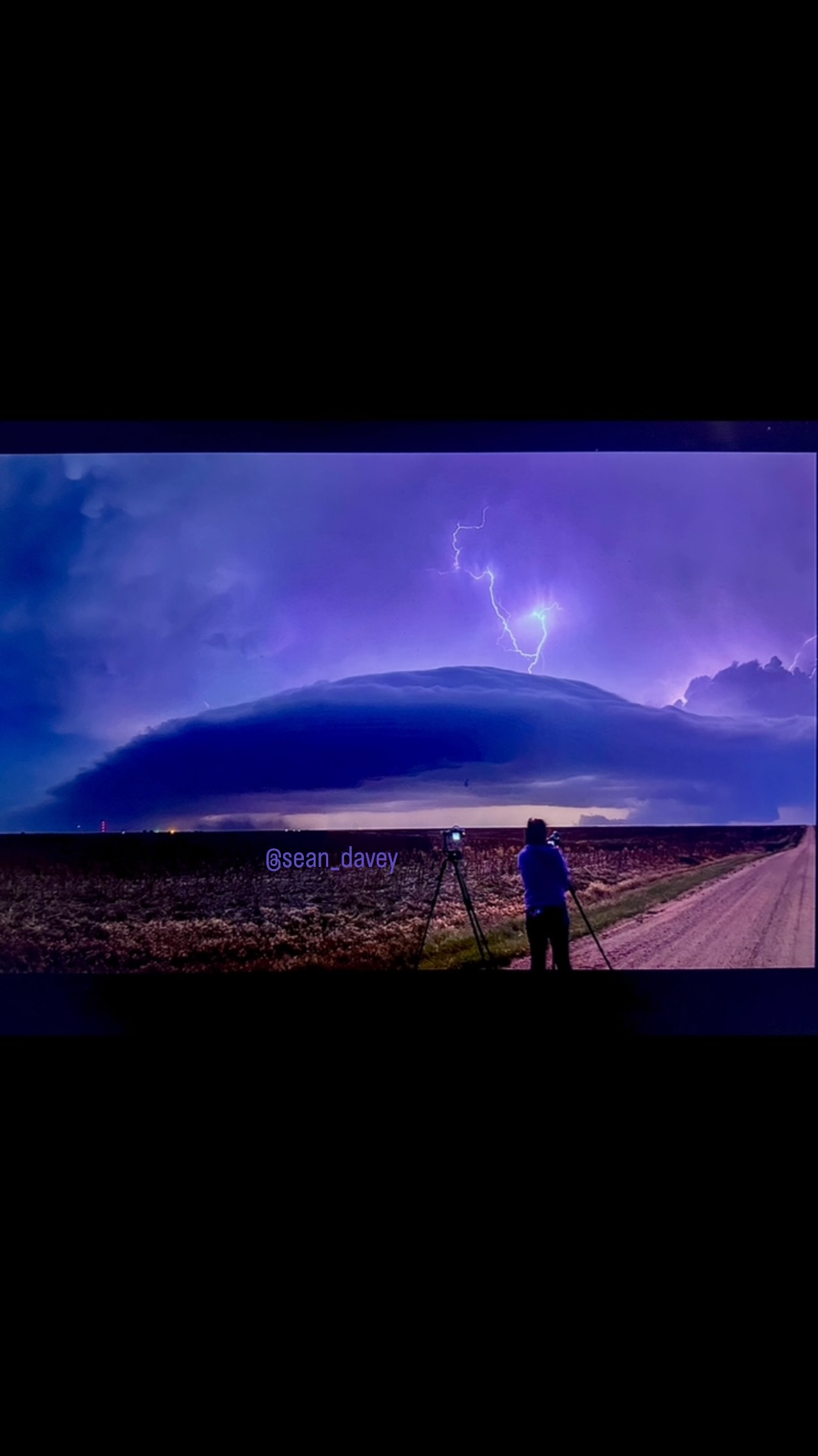 Lightning illuminating a storm above a photographer