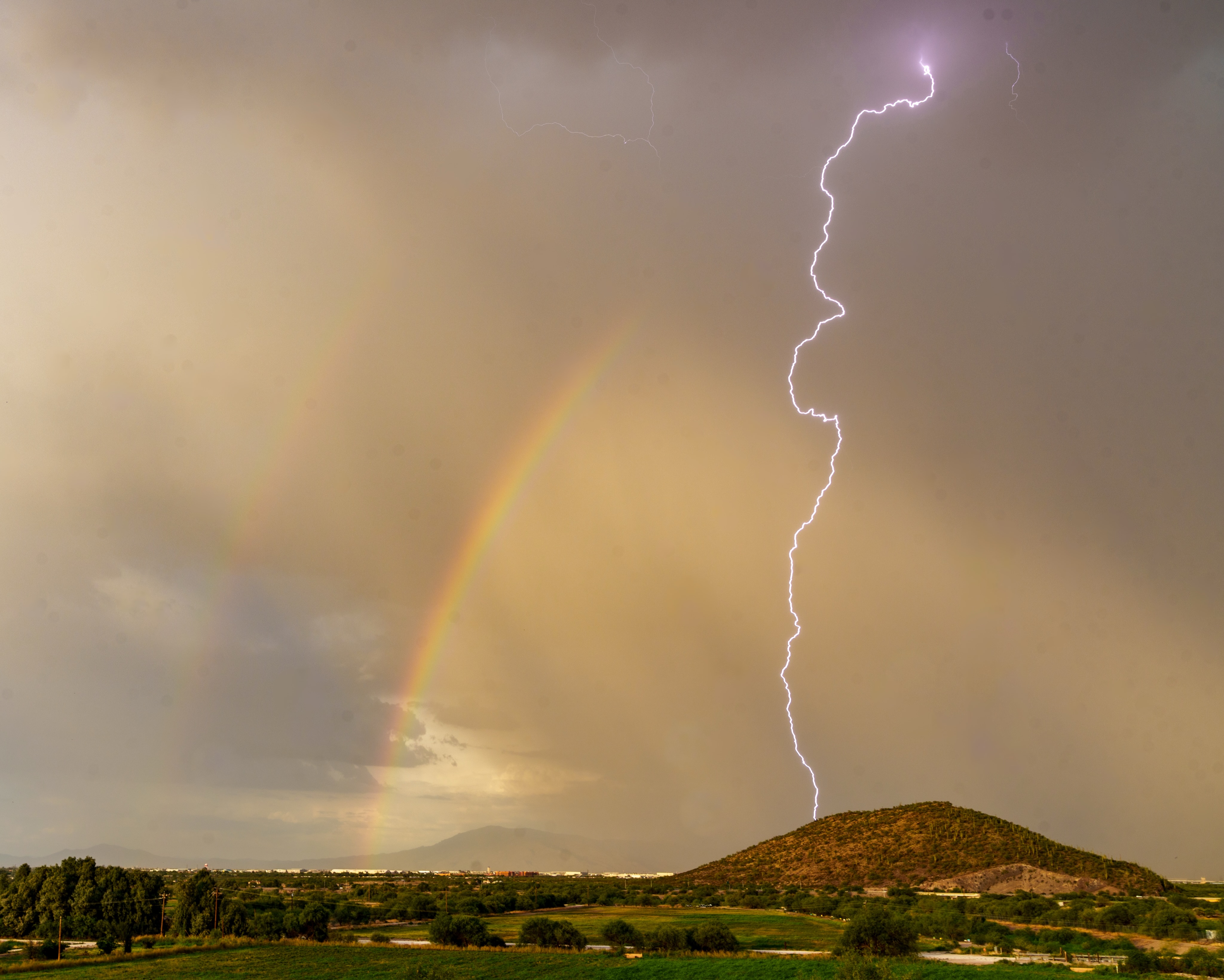 A rainbow and lightning bolt over the desert